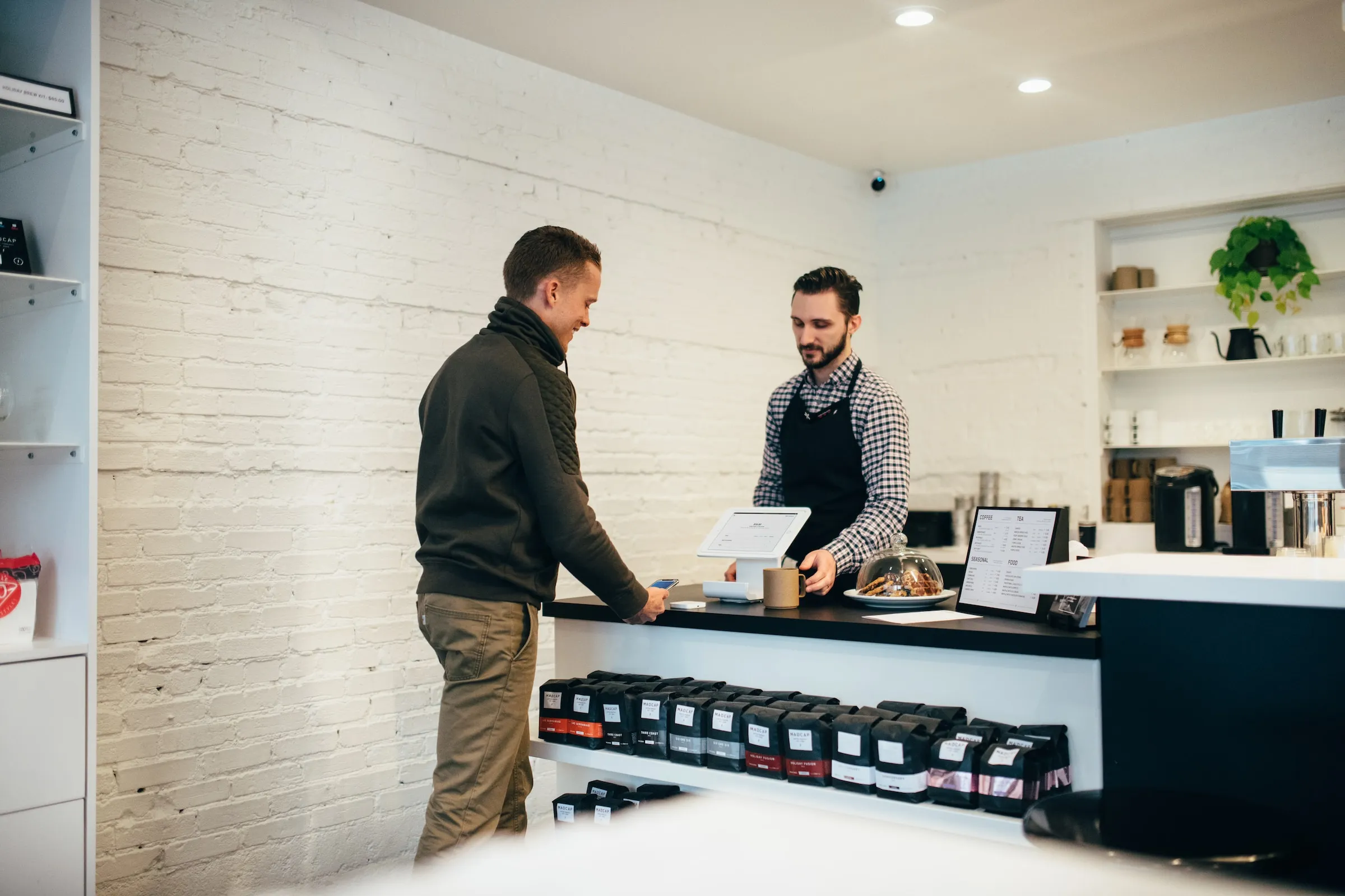 Two men in a cafe at a counter.