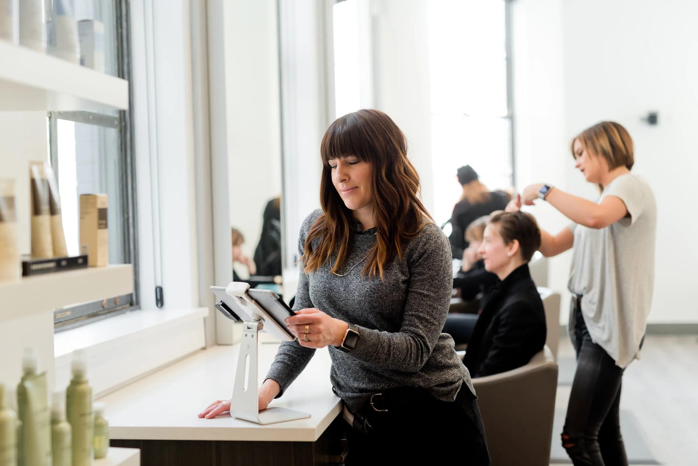 A confident female salon owner working on a tablet.